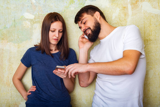 Молода пара в повсякденному одязі використовує свої смартфони вдома
 - Фото, зображення