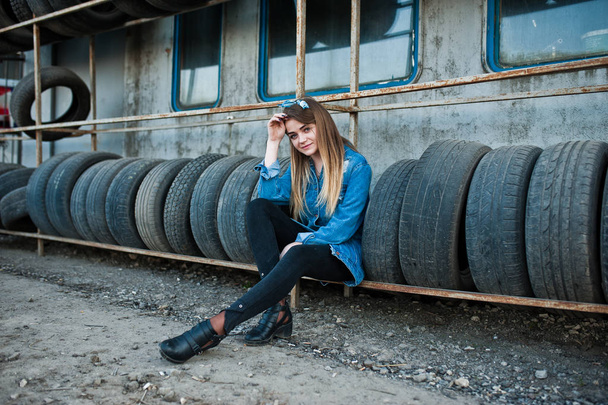 Young hipster girl in jeans jacket and head scarf at tire fitting zone. - Foto, Imagem