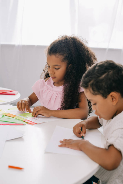 アフリカ系アメリカ人の子供たちが教室でカラフルな鉛筆で絵を描く - 写真・画像