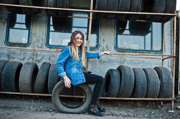 Young hipster girl in jeans jacket and head scarf at tire fitting zone. - Fotografie, Obrázek