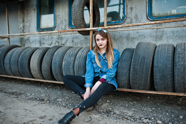 Young hipster girl in jeans jacket and head scarf at tire fitting zone. - Foto, Imagen