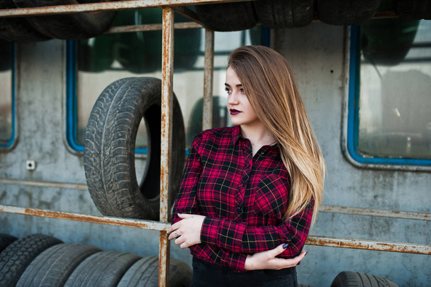 Young hipster girl in checkered shirt at tire fitting zone. - Фото, изображение
