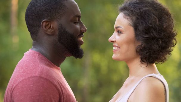 Homem e mulher multiétnicos olhando um para o outro com amor e ternura nos olhos
 - Foto, Imagem