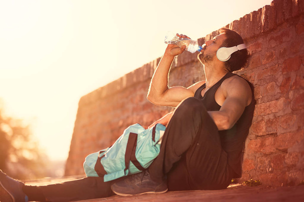 Thirsty healthy male with fit body drinking water, refreshing after heavy workout - Foto, imagen