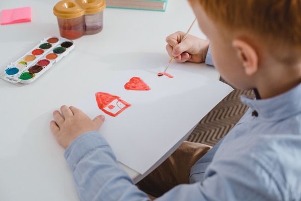 partial view of preschooler red hair boy drawing picture at table in classroom - Photo, Image