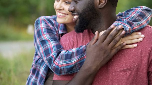 Homem negro e mulher de raça mista carinhosamente abraçando, pessoas felizes sorrindo juntas
 - Foto, Imagem