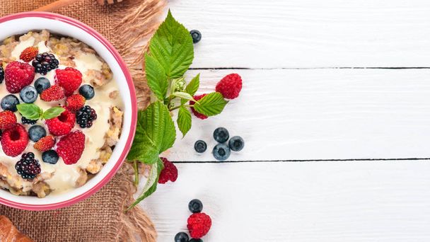 Oatmeal with yogurt and berries. Healthy food. On a wooden background. Top view. Free space for text. - Fotoğraf, Görsel