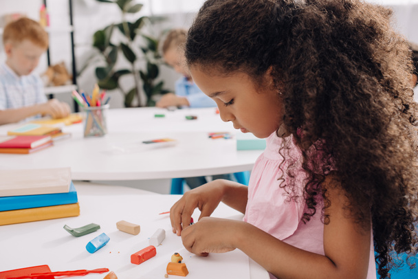 enfoque selectivo de niño afroamericano con figura escultórica de plastilina en la mesa en el aula
 - Foto, Imagen