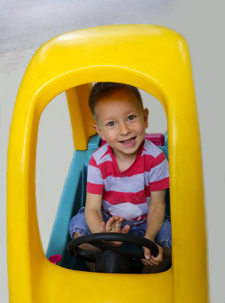 Милий усміхнений маленький хлопчик грає в машині
 - Фото, зображення