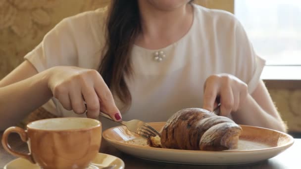 Fiatal nő eszik croissant, és énekel kávé, kávézó - Felvétel, videó
