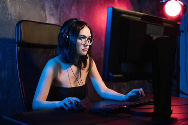 Professionele meisje Gamer speelt in Mmorpg of strategie videogame op haar Computer. Shes deelnemen aan Online Cyber Games toernooi, speelt thuis, of op Internet Cafe. Ze draagt Gaming Headset - Foto, afbeelding