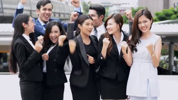 Молодая азиатская китайская бизнес-команда аплодирует, улыбается, взволнован и очень счастлив после успешного проекта сделки, давая друг другу пятерки. Средний выстрел, снят на улице. Поза драматического счастья
. - Кадры, видео