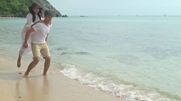 Attractive young couple having fun on beach. Running on beach. Young chinese woman with White man in early 20s. Mixed race. Shot in slow motion. Film look. - Felvétel, videó