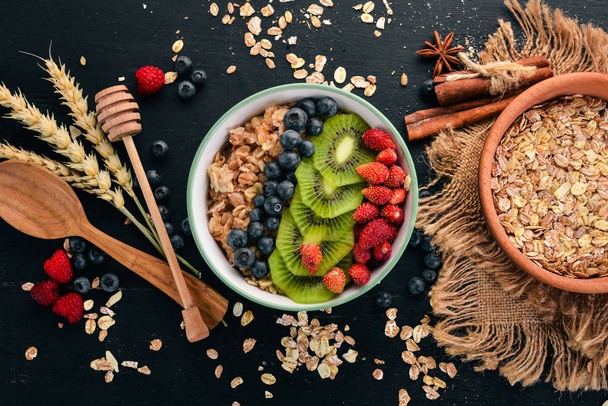 Oatmeal with blueberry strawberries and kiwi. On a wooden background. Top view. Free space for text. - 写真・画像