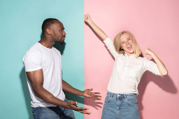 We won. Winning success happy afro man and woman celebrating being a winner. Dynamic image of caucasian female and male model on pink studio. - Fotografie, Obrázek