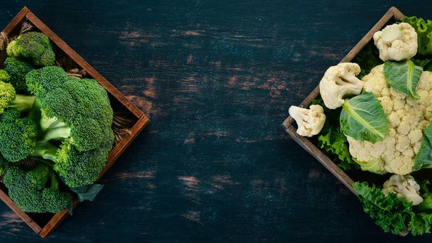 Cauliflower and broccoli in a wooden box. Fresh vegetables. On a wooden background. Top view. Copy space. - Fotoğraf, Görsel