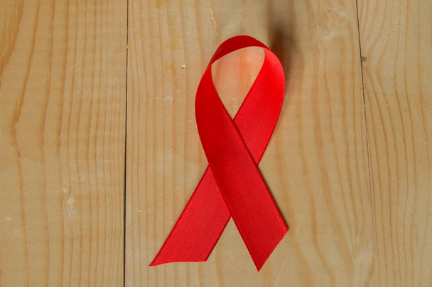 木材の背景に赤いリボンを意識: 12 月に Hiv とともに生きる人々 の健康のため国民の支持にエイズ キャンペーンに対する戦いの世界の日 - 写真・画像