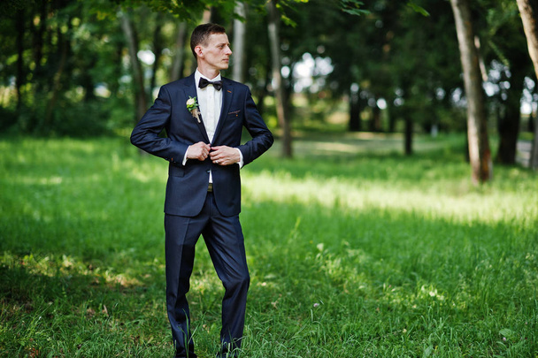 Portrait of a handsome groom posing alone in the park on the wedding day. - Fotó, kép