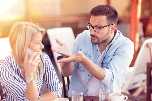 frustrated man criticizes his girlfriend who constantly talks over the phone, young couple at coffee shop with internet and mobile phone addict woman ignoring man  - Foto, Bild
