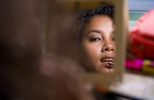 lifestyle portrait of mirror reflection of young happy and beautiful latin American woman carefully  using lipgloss pencil on her lips applying face makeup in female beauty skin care concept - Photo, Image