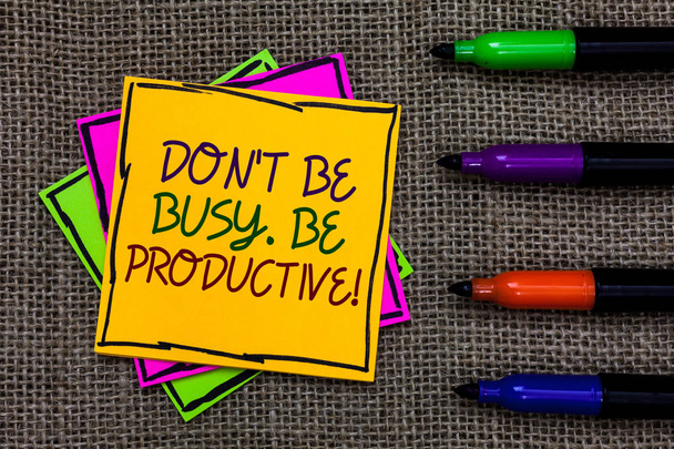 Text sign showing Don t not Be Busy. Be Productive. Conceptual photo Work efficiently Organize your schedule time Written on some colorful sticky note 4 pens laid in rank on jute base - Photo, Image