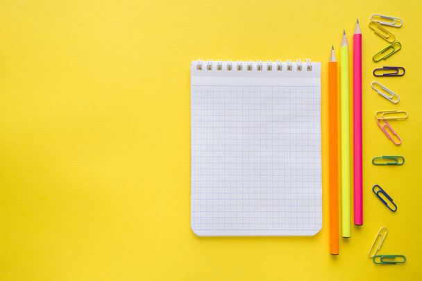 Notizbuch, Bleistifte farbige Büroklammern auf gelbem Hintergrund. - Foto, Bild