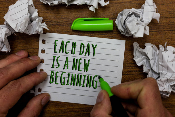 Word writing text Each Day Is A New Beginning. Business concept for Every morning you can start again Inspiration Hand hold green pen and words on white page paper lobs around on wooden desk - Photo, Image