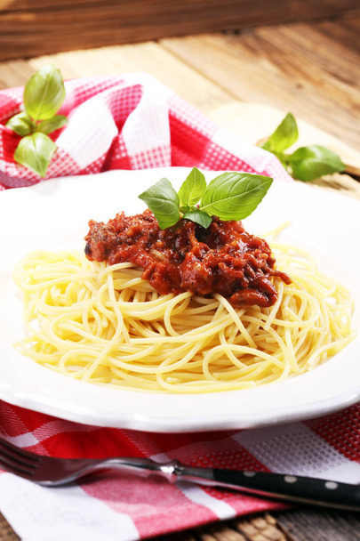 Plaat van heerlijke spaghetti Bolognaise of Bolognese met hartige gehakt en tomatensaus gegarneerd met Parmezaanse kaas en basilicum - Foto, afbeelding