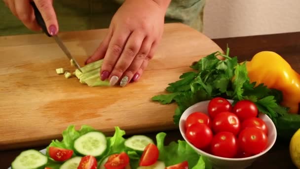 A woman cuts the avacado peeled from its peel, to make a salad - Séquence, vidéo