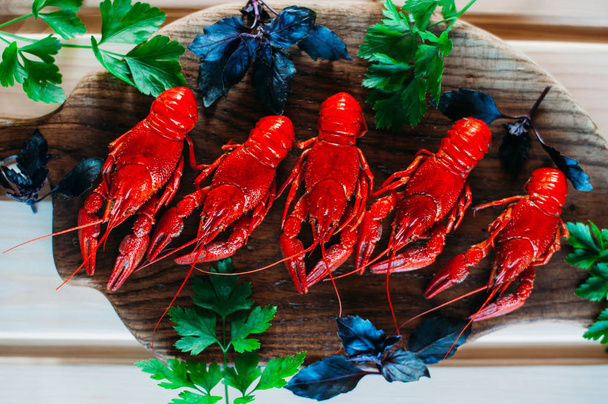 Красные раки, вареные на кухонной доске с базиликовым укропом
 - Фото, изображение