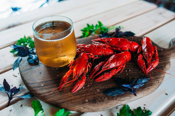 crayfish red boiled on a kitchen board with basil dill with a glass of beer - Foto, Imagen