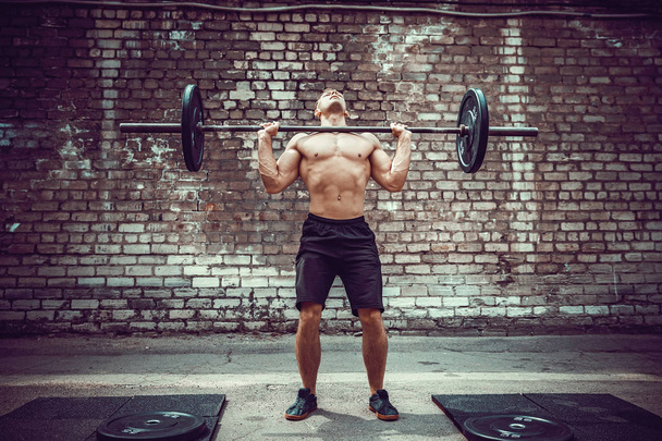 Muscular fitness man doing deadlift a barbell over his head in outdoor, street gym. Functional training. - Fotografie, Obrázek