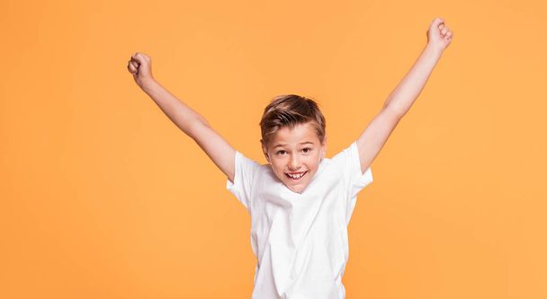 Little school boy jumping in the studio on a yellow background. Concept of happy childhood. - Foto, imagen