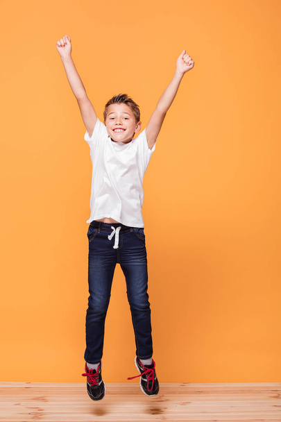 Little school boy jumping in the studio on a yellow background. Concept of happy childhood.  - Foto, Bild