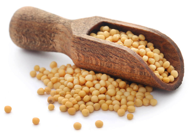 Golden mustard seeds in a wooden scoop over white background - Photo, Image