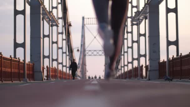 Slim senior female running across bridge in city - Filmati, video