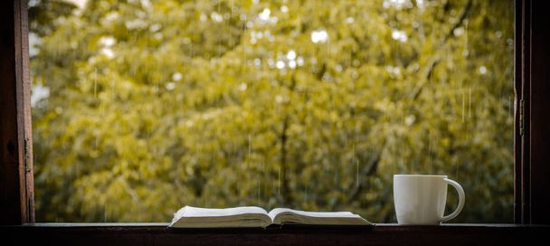 Nature morte d'automne confortable : tasse de café chaud et livre ouvert sur le rebord de la fenêtre vintage et la pluie à l'extérieur. Automne. Appartement. Pluie
  - Photo, image