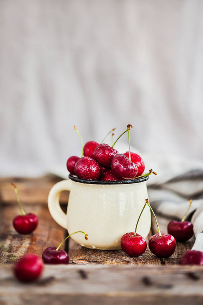 Fresh ripe cherries in a mug on rustic backgroun - Foto, Imagem