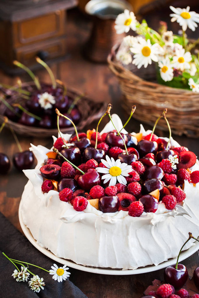 Deliziosa torta di meringa Pavlova decorata con lamponi freschi e ciliegie su sfondo rustico
 - Foto, immagini