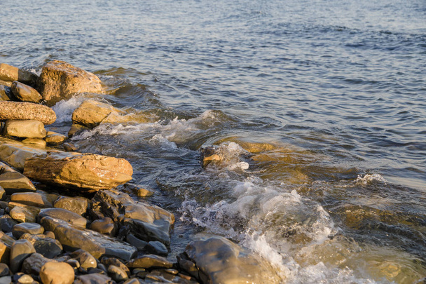 Κύματα της θάλασσας που αγωνίζονται ενάντια στα μεγάλα βράχια στην ακτή. - Φωτογραφία, εικόνα