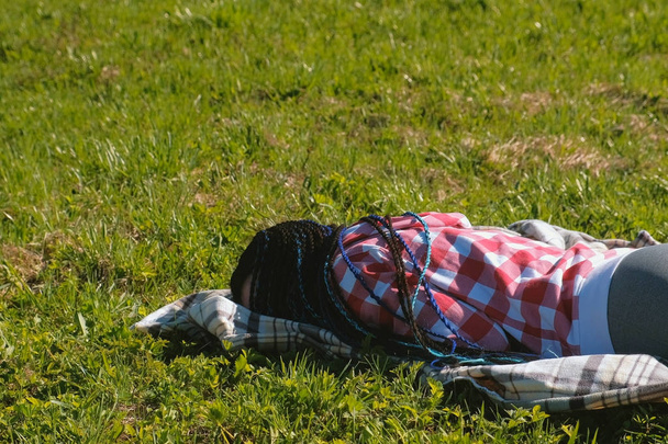 Unrecognizable woman with blue African braids sleeping on the lawn in the Park. - Foto, Imagem