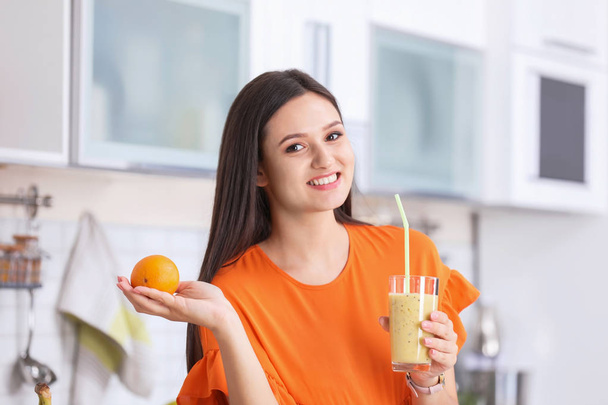 Young woman with glass of tasty healthy smoothie in kitchen - Foto, Imagen