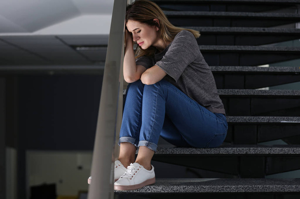 Lonely depressed woman sitting on stairs indoors - Photo, image