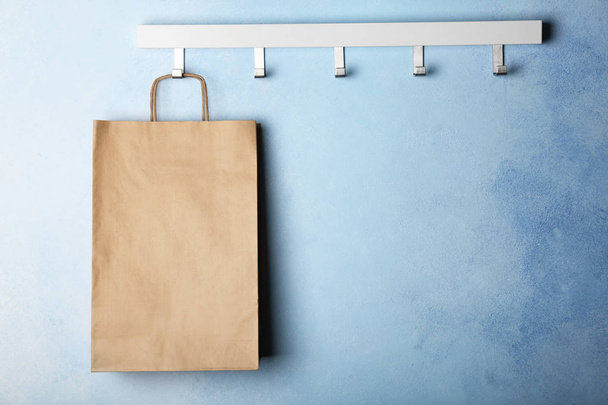 Rack with paper shopping bag on color wall - Φωτογραφία, εικόνα