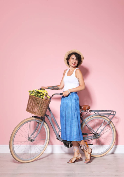Portrait of beautiful young woman with bicycle near color wall - Fotoğraf, Görsel