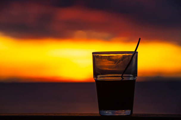 De achtergrond van silhouet glas koffie met lepel bij zonsopgang, close-up shot - Foto, afbeelding