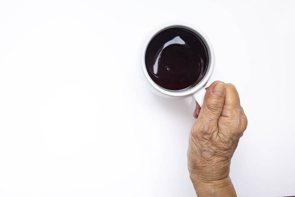 Main droite de la femme âgée tenant tasse de café noir isolé sur fond blanc
 - Photo, image