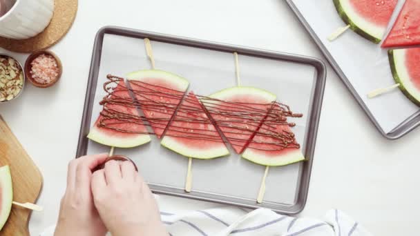 Stap voor stap. Watermeloen wiggen gegarneerd met chocolade en zee zout op de stick op het bakken blad. - Video