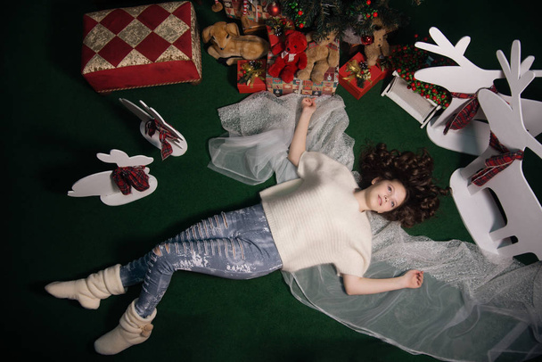 дівчата лежать поруч з ялинкою з подарунками
 - Фото, зображення