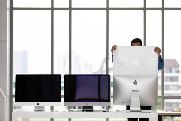 BANGKOK, THAILAND - toukokuu 05, 2018: Aasian nuori liikemies perusti kaksi uutta iMac-tietokonetta virkaan. Toinen on iMac Pro, joka on iMac-tuotantolinjan huippumalli, kallis mutta nopeampi ja suorituskykyisempi
. - Valokuva, kuva